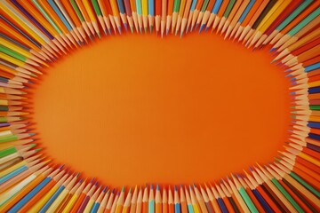 Colorful pencils arranged in oval frame on orange background. (1)