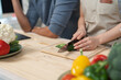 © crizzystudio - Close-up of a chef's hands skillfully slicing fresh zucchini on a wooden cutting board, surrounded by vibrant vegetables, embodying culinary expertise and healthy eating