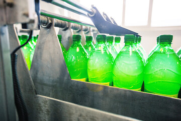 Poster - bottles filled with green liquid move through a production line at a beverage manufacturing facility