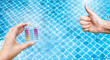 © sirirak - Mini tester in girl hand with thumbs up hand over clear swimming pool water background, good quality water, water tester test kit