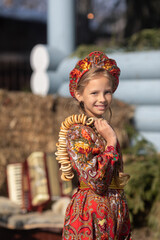 Wall Mural - A blonde girl in a national Russian costume on the Maslenitsa holiday. A beautiful russian girl in a national costume made of a fur cape and kokoshnik on the background of a hayloft. 