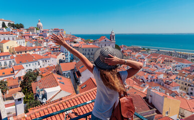 Wall Mural - young woman with a hat enjoying the rooftop view of lisbon's old town