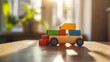 © huhu - Colorful wooden toy truck carrying blocks on a table in sunlight.