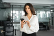 © Stock 4 You - Young Indian business woman manager ceo using cell phone mobile app laptop. Smiling Latin Hispanic mature female businesswoman holding smartphone in office trading, reading, working online. Copy space