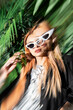 © ADDICTIVE STOCK - Stylish woman in sunglasses standing by greenery with motion blur