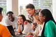 © Jose Calsina - Big group of teenage students talking together sitting on a university campus bench. Young friends having fun on a social gathering outside. Classmates having a conversation on a friendly meeting