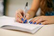 © ADDICTIVE STOCK - Person writing in notebook with a pen and manicured nails