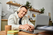 © LIGHTFIELD STUDIOS - Bright and cheerful young man immerses himself in remote work while listening to music.