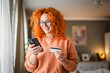© Miljan Živković - smile redhead woman use mobile phone and credit card for payment