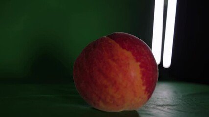 Poster - Vibrant peach rests on green background under bright light showcasing its natural colors