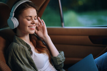 Poster - Young woman enjoying music with headphones while relaxing in a car, expressing happiness and tranquility in a natural setting.