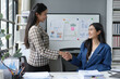 © amnaj - Two businesswomen shaking hands after successful meeting in office