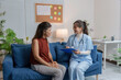 © amnaj - Female doctor holding clipboard and taking notes while talking with patient in hospital