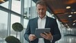 © SebuahKisah - Confident middle-aged man using a digital tablet in a modern office building