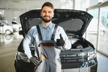 Leinwandbilder - Friendly mechanic in modern car repair shop with car. Professional technician checking vehicle diagnostics and maintenance. Concept of automotive industry and customer service