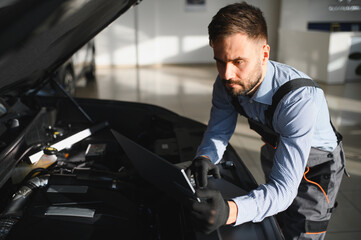 Leinwandbilder - Friendly mechanic in modern car repair shop with car. Professional technician checking vehicle diagnostics and maintenance. Concept of automotive industry and customer service