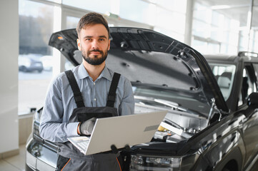 Fototapete - Auto mechanic using computer diagnostic program while repairing car in workshop