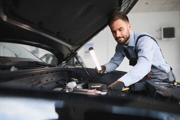 Fototapete - Friendly mechanic in modern car repair shop with car. Professional technician checking vehicle diagnostics and maintenance. Concept of automotive industry and customer service