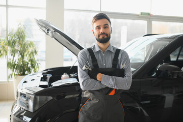 Leinwandbilder - Friendly mechanic in modern car repair shop with car. Professional technician checking vehicle diagnostics and maintenance. Concept of automotive industry and customer service