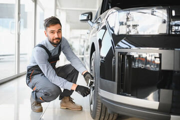 Leinwandbilder - Car mechanic working in garage and changing wheel alloy tire. Repair or maintenance auto service. Replacement of winter and summer tires