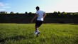 © ExpressVectors - Professional footballer in uniform shows tricks with ball while running at green field. Sportsman kicks ball during jogging at meadow on sunny day. Young man training at stadium. Freestyle football