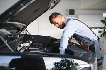 Leinwandbilder - Friendly mechanic in modern car repair shop with car. Professional technician checking vehicle diagnostics and maintenance. Concept of automotive industry and customer service