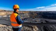 © Matthew - A worker observes a mining site from above, with heavy machinery operating below.