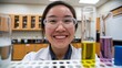 © Tom - A young Asian female scientist smiles in the laboratory, surrounded by colorful test tubes filled with various solutions, showcasing a bright and innovative atmosphere.
