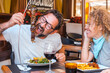 © simona - Friends enjoying a laid-back meal at a restaurant, with the man biting into a skewer of grilled meat and the woman laughing in the company of each other.