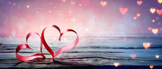 Wall Mural - valentine's day - two ribbon hearts with magic bokeh lights on wooden table and abstract defocused g