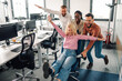 © Zamrznuti tonovi - Business colleagues pushing businesswoman on office chair, having fun at work