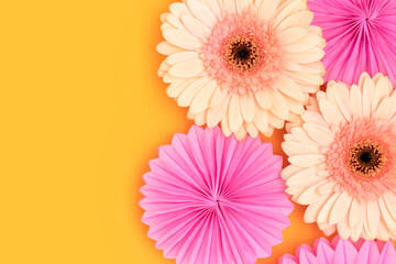 Wall Mural - gerbera flowers and tissue paper fans on a yellow background. festive composition with copy space.