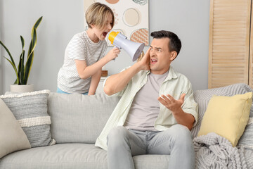 Canvas Print - Young man stressed of his noisy little son with megaphone at home