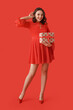 © Pixel-Shot - Pretty young woman with gift box on red background