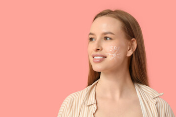 Wall Mural - Beautiful young happy woman with sunscreen cream on her face against pink background