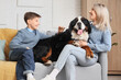 © Pixel-Shot - Little boy and his mother with Bernese mountain dog sitting on sofa at home