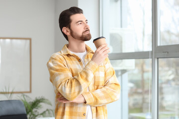 Sticker - Handsome man with cup of coffee looking upwards in office