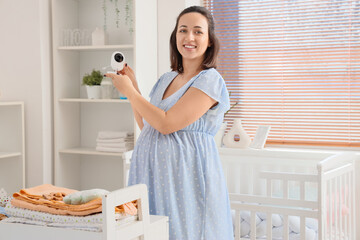 Canvas Print - Young pregnant woman with baby monitor in children's bedroom