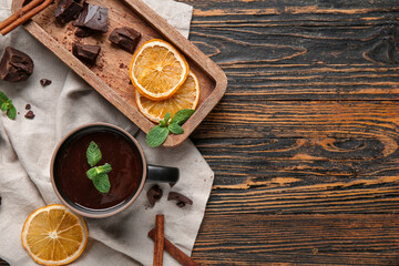 Canvas Print - Cup of hot chocolate with mint leaves, dried orange slices and cinnamon sticks on wooden background