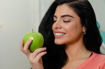 Gorgeous Caucasian, dark hair woman holding green apple , having perfect teeth, dentistry concept 