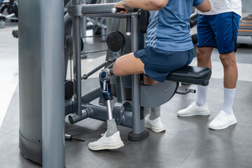 a female person with prosthetic leg doing fitness exercise equipment with a personal trainer