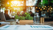 © Wasin Arsasoi - Modern Workspace in Cafe: A close-up shot focuses on financial documents and a glass of water on a wooden table in a bustling cafe, with a blurred background of colleagues collaborating.