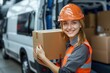© kornc - A smiling woman in safety gear carries a cardboard box next to a delivery van, showcasing a positive attitude in logistics and transportation.
