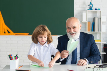 Fototapete - Happy kid in school. Teacher with pupil with airplanes. Education, teachering, elementary school.