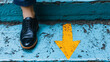 © CreativeIMGIdeas - Following the Arrow: A close-up shot of a person's foot in a polished black Oxford shoe positioned above a bright yellow arrow painted on weathered blue steps, symbolizing direction and progress.