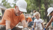 © pattozher - Helping Hands:  A close-up of a construction worker,  wearing a hard hat and orange shirt,  working diligently on a project with a  focused and  determined expression.
