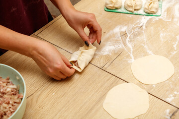 Wall Mural - A woman is making dumplings on a wooden table