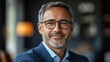 © kinkin - Portrait of a smiling middle-aged man wearing glasses and a suit.