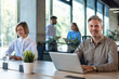 © ty - Businesspeople in formalwear working on laptop and PC in the modern office with colleagues on the background.