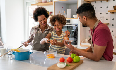 Wall Mural - happy african american parents and child having fun preparing healthy food in kitchen